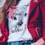 Rote Trachtenjacke, weißes T-Shirt mit Motiv und blaue Trachtenjeans